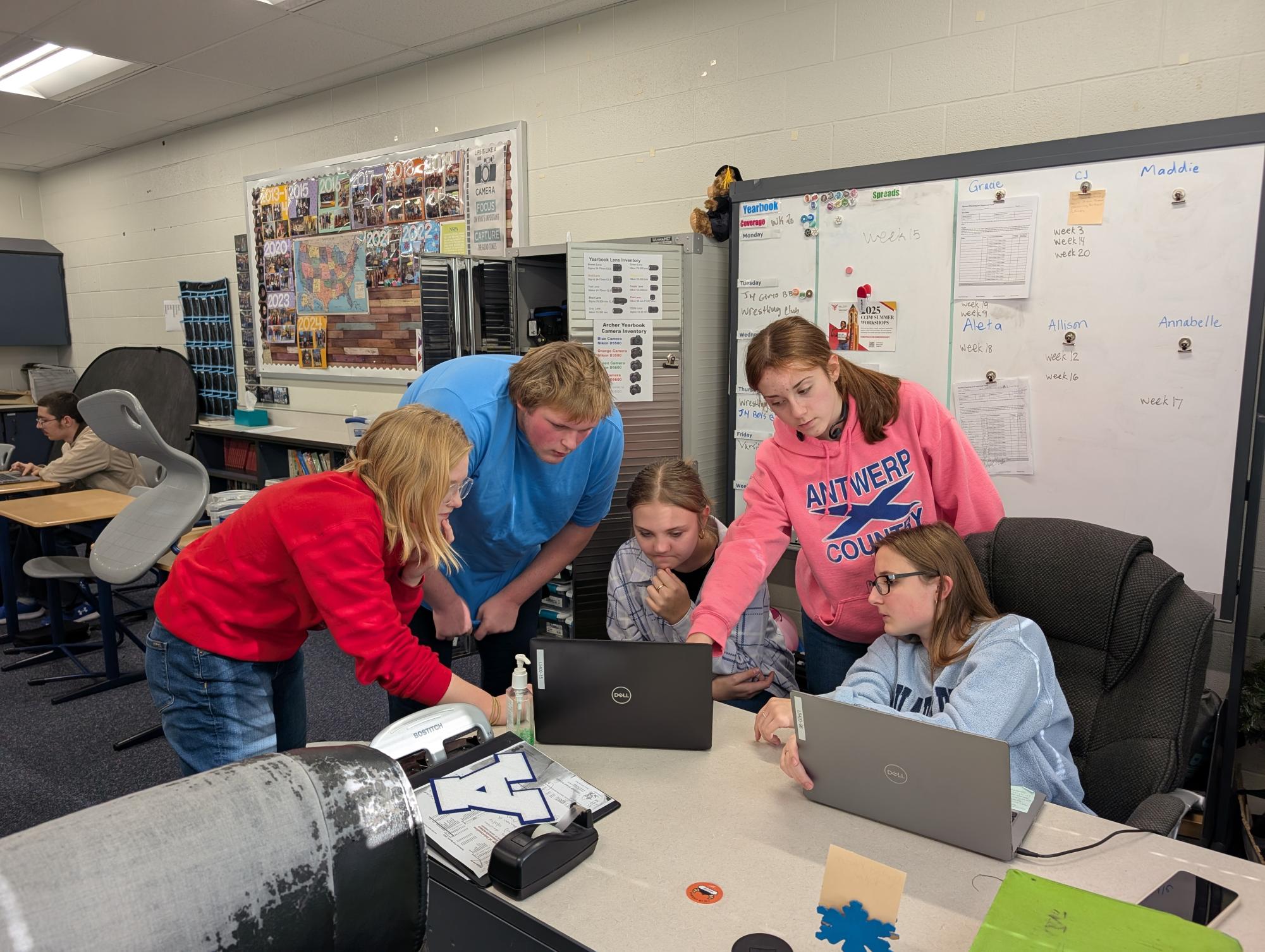 Members of The Archer yearbook staff collaborate with a former editor-in-chief to discuss strategies for redesigning a spread and improving its overall impact. 