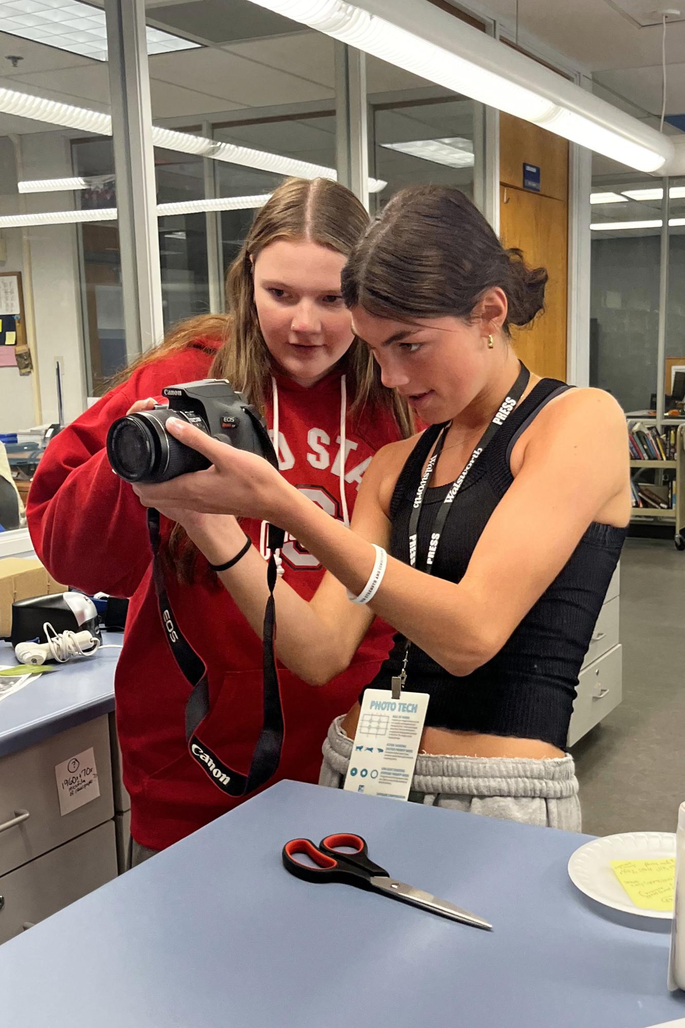 Granville High School senior Ruby Goodwin shows sophomore Reagan Smith how to adjust settings on a DSL camera. Returning yearbook staff members paired up with new staff members early in the year to help them learn photography skills. 